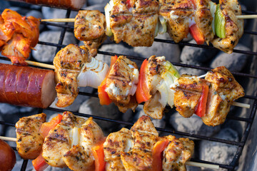 Grilled chicken skewers with vegetables on barbecue grill over hot coals, close-up of seasoned kebabs with onion and bell pepper during outdoor cooking.