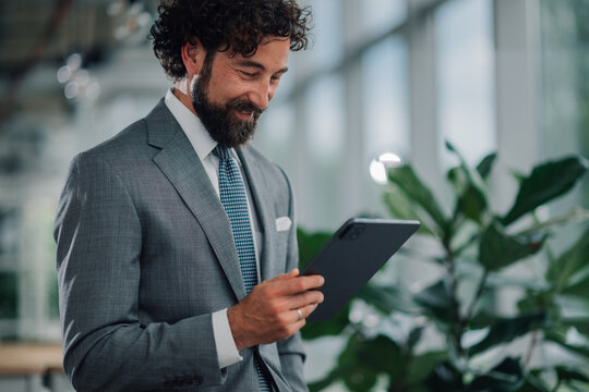 Smiling businessman using digital tablet in modern office - Powered by Adobe