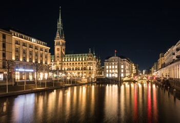 Fototapeta premium Nighttime long exposure of Hamburg City Hall reflecting in the Kleine Alster under a black sky, emphasizing the historic building’s illuminated grandeur. 