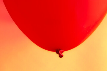 Primal coloured  red balloon contrasting against a sharp yellow paper textured background