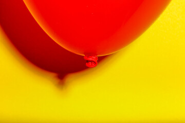 Primal coloured  red balloon contrasting against a sharp yellow paper textured background