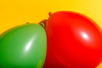 Balloons in primal colors green and red next to each other contrasting against a warm yellow paper textured background