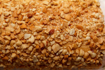 Crushed peanut-covered dessert surface texture in warm lighting.