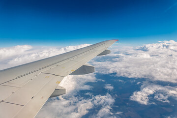 Fototapeta premium View from the airplane window at a beautiful cloudy sky and the airplane wing