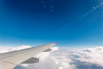 View from the airplane window at a beautiful cloudy sky and the airplane wing