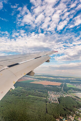 Fototapeta premium View of airplane wing, blue skies and green land during landing. Airplane window view.