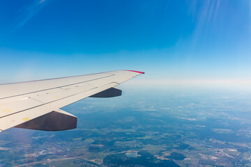 Fototapeta premium View from the airplane window at a beautiful blue clear sky and the airplane wing