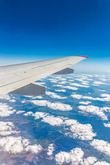 View from the airplane window at a beautiful cloudy sky and the airplane wing