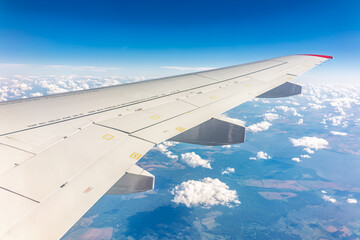 Obraz premium View from the airplane window at a beautiful cloudy sky and the airplane wing