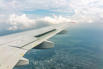 Obraz premium View of airplane wing, blue skies and green land during landing. Airplane window view.