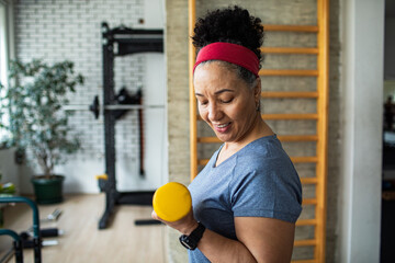 senior woman training in a gym using dumbbells