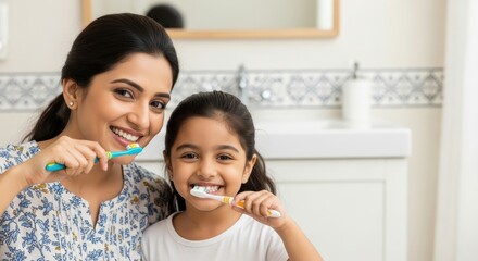 smiling indian mother and daughter brushing teeth together in bright bathroom. morning routine promoting dental hygiene. family health, lifestyle, personal care, parenting, healthcare