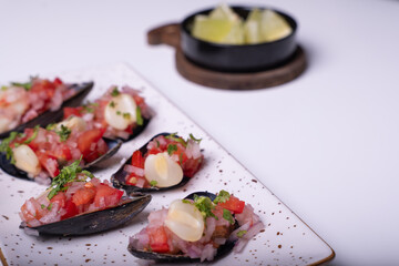 White tray of Choros a la chalaca on a white background.