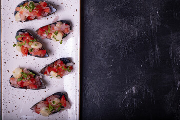 Top view of a white tray of Choros a la chalaca on a black background.