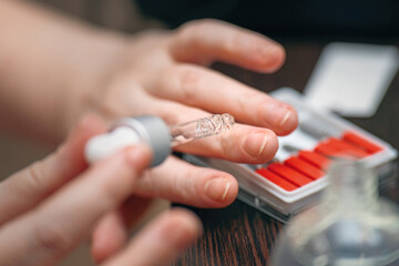 Obraz premium Girl carefully applying nail care balm with glass dropper for healthy cuticles and nourished nails
