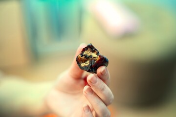 Hand holding traditional Caucasian snack churchkhela with visible fruit and nuts, bite taken from...