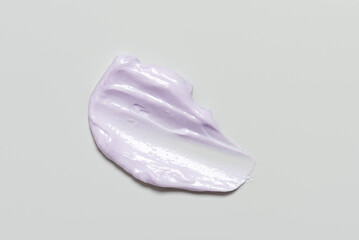 Fototapeta premium Smear of cosmetic purple cream on gray background, top view, texture moisturizer