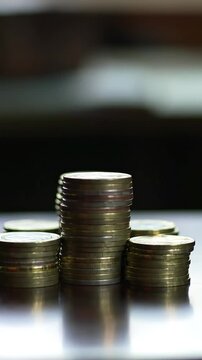 Completing the Stack: A hand carefully places the last coin atop a precisely aligned currency pile, signifying financial success and meticulous money management.