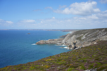 Fototapeta premium A scenic view of a rugged, rocky headland extending into the blue sea along the coast of Brittany, France.