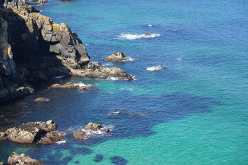 Obraz premium A stunning high-angle view of a cove in Brittany, showing incredibly clear turquoise water over submerged rocks.