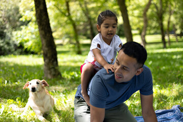 Happy latin family enjoying a sunny day at the park with their dog