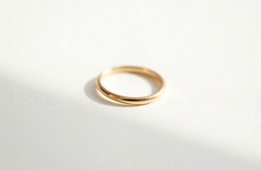 Thin gold band ring closeup. Minimalist jewelry on pristine white background. Smooth metallic accessory, elegant object, subtle sparkle, shiny, pure gold.