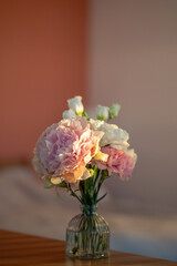 Compact bouquet of peony carnation lisianthus arranged in clear glass vase on table under sunlight. Floral composition of decorated romantic flowers, home interior styling with spring bouquet