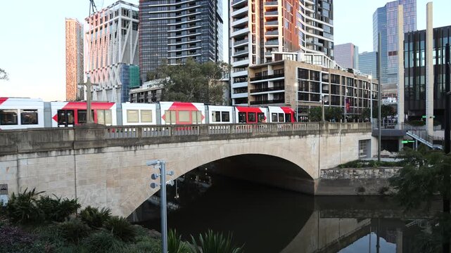 Parramatta city CBD Church Street tram on Lennox bridge at sunset over river.
