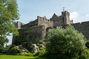 Fototapeta premium Exploring the ancient stone fortress surrounded by lush greenery under a bright blue sky