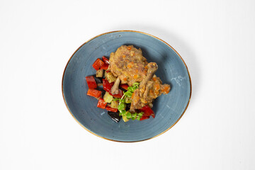 Stewed chicken in sauce with braised vegetables on a plate on white background