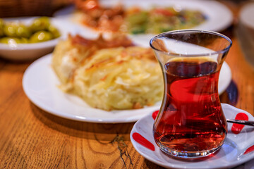 Traditional tulip shaped glass of Turkish tea or chai served in a tulip glass with borek pastry and olives, breakfast at a restaurant, Istanbul Turkey