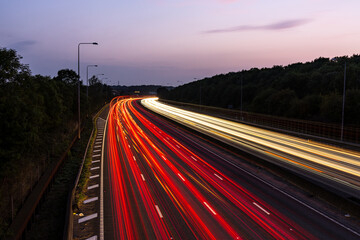 Light trails illuminating highway at dusk with purple sky