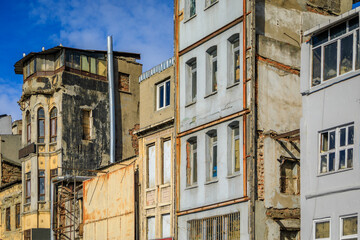 A row of old buildings with weathered crumbling facades and peeling paint shows decay of aging urban architecture in Karakoy, Istanbul, Turkey