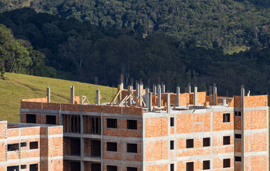reinforced concrete and masonry buildings being constructed in front of a large area of preserved forest
