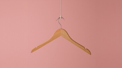 Natural Wood Coat Hanger with Metallic Hook on Muted Pink Backdrop