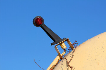A bold red circular tail light is attached to a yellow industrial tank, with exposed wires trailing...