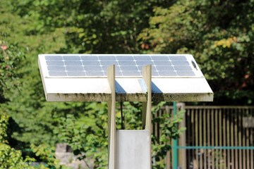 A single photovoltaic solar panel on wooden supports provides off-grid electricity to electronic...