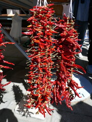 Red chili peppers stringed up for display in outdoor farmers market vertical photo