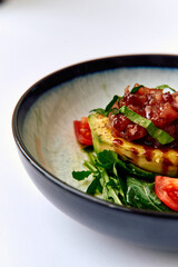 A Vibrant Dish of Grilled Avocado Topped with Fresh Salsa and Garnished with Tomatoes and Herbs Presented in a Stylish Bowl