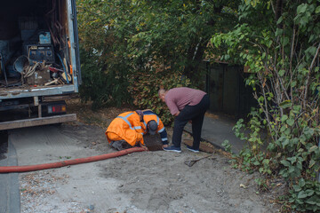 Sewer workers cleaning manhole and unblocking sewers the street sidewalk