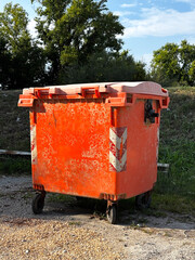 A household waste bin placed on the side of the road. A typical urban container used for household waste disposal.