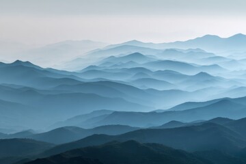 Fototapeta premium Misty blue mountain layers under morning fog creating a serene landscape.
