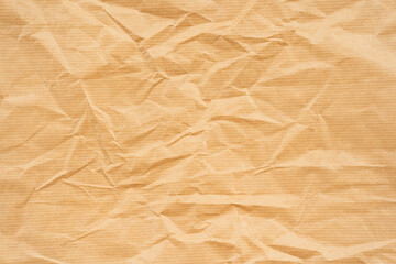 Obraz premium Crumpled brown kraft paper with visible creases and textured surface. Suitable for design projects, packaging mockups, or backgrounds