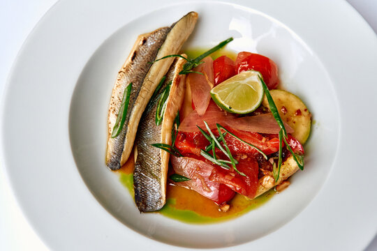 Elegant Seafood Dish Featuring Seared Fish, Fresh Vegetables, and Citrus Garnish, Highlighting Culinary Artistry and Fresh Ingredients on a Plate
