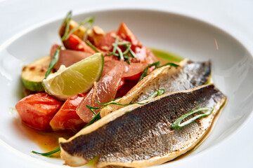 A Delicate Plate of Grilled Fish Accompanied by Fresh Tomato and Lime Garnish, Capturing the Essence of Culinary Artistry and Flavorful Presentation