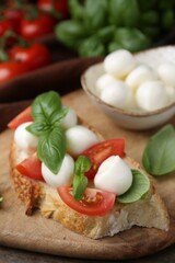 Tasty sandwich with mozzarella cheese, tomatoes and basil on wooden table, closeup