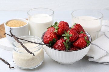 Different ingredients for panna cotta. Milk, sugar, vanilla and strawberries on white tiled table, closeup