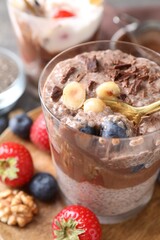 Taking delicious chocolate pudding with chia seeds, blueberries and hazelnuts from glass on table, closeup