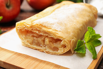 Tasty apple strudel with powdered sugar and mint on table, closeup