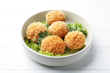 Delicious fried croquette balls with parsley and lettuce on white wooden table, closeup